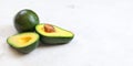 Avocados, one whole, other cut in half, seed visible on white board. Wide banner with space for text on right side