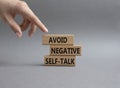 Avoid negative self-talk symbol. Concept words Avoid negative self-talk on wooden blocks. Beautiful grey background. Businessman