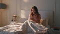 Awake woman typing phone in morning sunlight. Smiling calm girl resting in bed Royalty Free Stock Photo