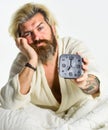 Awakening concept. Insomnia sleep disorder. Healthy habits and lifestyle. Bearded man with alarm clock. General