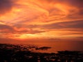 Sunset with flaming cloudy sky and deep burn rocky shore. Casuarina beach. Darwin, Australia Royalty Free Stock Photo