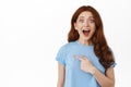 Awesome discounts. Amazed redhead girl gasp and say wow, checking out promo logo, pointing finger left and react to