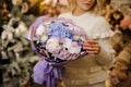 Awesome flower bouquet wrapped in lilac paper in the hands of woman