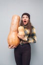 awesome girl holding big and small pumpkins on a gray background.