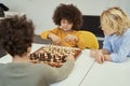 Awesome little children discussing game while sitting at the table and playing chess indoors Royalty Free Stock Photo