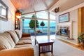 Awesome living room interior with sloped wooden ceiling and water view.