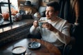 Awesome man sitting in cafe and drinking hot tea in front of window Royalty Free Stock Photo