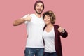 Awesome. Portrait of positive couple of friends in casual style standing, hugging and showing thumbs up with toothy smile, looking