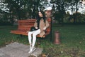 Awesome portrait of young lady, sitting on the wooden bench at the park.Soft colours, awesome place