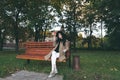 Awesome portrait of young lady, sitting on the wooden bench at the park.Soft colours, awesome place