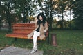 Awesome portrait of young lady, sitting on the wooden bench at the park.Soft colours, awesome place