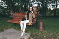 Awesome portrait of young lady, sitting on the wooden bench at the park.Soft colours, awesome place