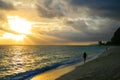 Awesome sunset beach walk after tropical storm, golden sun rays sunbeams opening dark cloudy sky