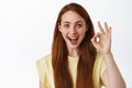 Awesome, very good. Smiling ginger girl shows okay no problem gesture, praise and compliment choice, say yes, approve