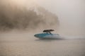 awesome view on boat quickly floating on the water against the backdrop of silhouette of hill in fog