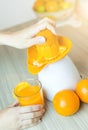 Awesome woman in the kitchen squeezing fresh orange juice with an electric juicer