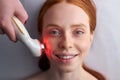 Awesome woman receiving stimulating electric facial treatment in spa salon