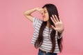 Awful smell! Portrait of confused girl with brunette hair pinching her nose to hold breath and showing stop gesture