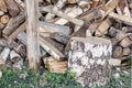 An ax in a wooden beam against the background of a pile of wooden firewood. Royalty Free Stock Photo