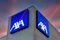 Axa logo on illuminated signs on building on colorful after sunset
