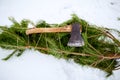 Axe on cut down spruce or pine christmas tree branches on snowy ground. Deforestation ban. Irresponsible behavior