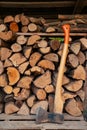 Axe in front of a stack of wood in a woodshed. Natural vertical background. Royalty Free Stock Photo