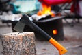 Axe on Tree Stump With Camping Fire Pit Burning in Background