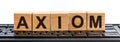 Axiom word made with building blocks. A row of wooden cubes with a word written in black font is located on a black keyboard