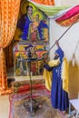 AXUM, ETHIOPIA - MARCH 19, 2019: Priest showing colorful paintings in the Old Church of St Mary of Zion in Axum, Ethiop