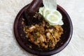 Ayam geprek sambal ijo. Fried chicken mixed with green chili sauce placed in clay mortar.