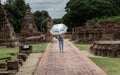 Rear view of Tourist woman holding silver umbrella and walking at Wat Ratchaburana