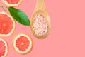 Ayurveda face skin scrub ingredients Himalayan salt in wooden spoon sliced grapefruit green leaf on cherry pink background Royalty Free Stock Photo