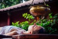 Ayurveda massage alternative healing therapy.beautiful caucasian female getting shirodhara treatment lying on a wooden Royalty Free Stock Photo