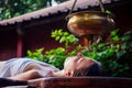 Ayurveda massage alternative healing therapy.beautiful caucasian female getting shirodhara treatment lying on a wooden