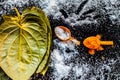 Ayurvedic remedy for sour throat consisting of betel leaves, turmeric, and salt on a black wooden surface.