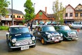 Three classic green Mini Austin cooper parked in Mini Mountain 4.0 festival with people and Vintage home background