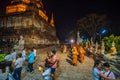 Buddhists people walking with lighted candles in hand around a ancient temple