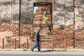 Ayutthaya, Thailand - February, 05, 2022 : Old man walking on the road ahead Buddha statues at the abandoned temple at Ayutthaya,