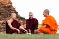 Ayutthaya, Thailand - JANUARY 17, 2017: Three Monks talking and teaching religion of the Buddhism, Monks sitting on the grass in