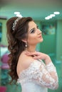 The bride puts her hand on her shoulder and takes a picture at the wedding. Wedding photo session in a beauty salon.The bride put