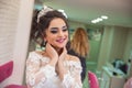 The bride puts her hand on her shoulder and takes a picture at the wedding. Wedding photo session in a beauty salon. The bride put