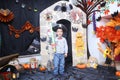 A child in the form of a witch on a broomstick, poses against the backdrop of pumpkins on Halloween holiday . Boy is