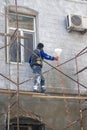 Azerbaijan, Baku-March 11, 2018; a worker repairs the wall of an old house by applying a white plaster mortar with an air spray.
