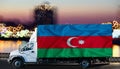 Azerbaijan flag on the side of a white van against the backdrop of a blurred city and river. Logistics concept