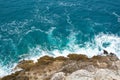 Azure blue sea waves crash on the rocks. Beautiful white foam spreads in all directions. Sea background. Royalty Free Stock Photo