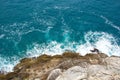 Azure blue sea waves crash on the rocks. Beautiful white foam spreads in all directions. Sea background. The view from the top Royalty Free Stock Photo