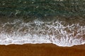 Azure clear sea with white waves and orange beach view from top.