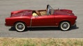 Exclusive convertible red Fiat, a roadster of the Sixties, on the roadside,