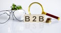 B2B concept on wooden cubes and flower ,glasses ,coins and magnifier on the white background Royalty Free Stock Photo