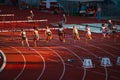 Female Sprinters Engaged in 100m Hurdles Race: Athletes Compete on Track and Field Circuit Royalty Free Stock Photo